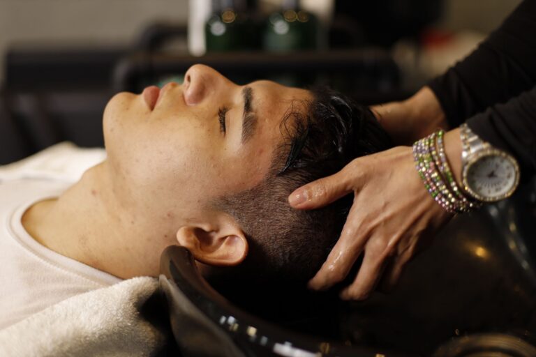 Homme les yeux fermés pendant un massage du cuir chevelu au bac de lavage