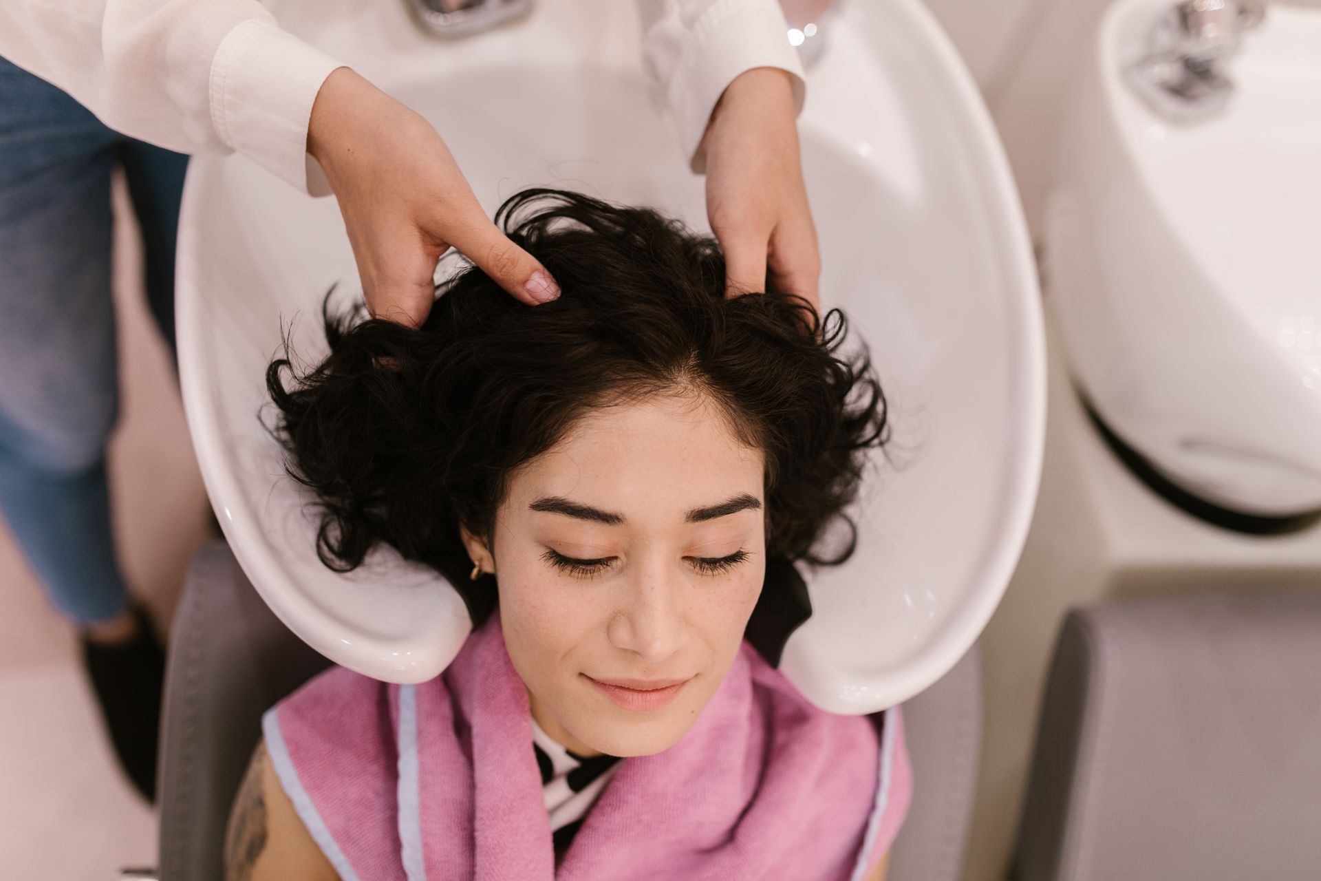 Femme détendue au bac à shampoing pendant un massage du cuir chevelu de head spa