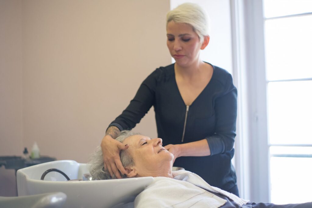 Praticienne massant la tête d'une cliente allongée au bac pendant un soin head spa