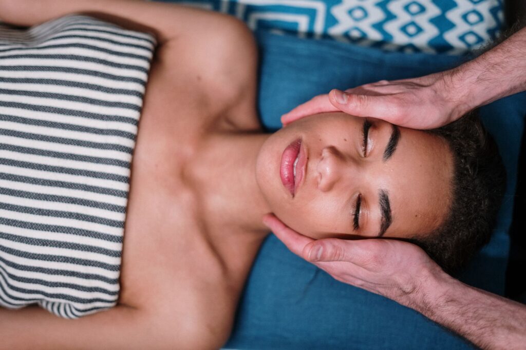 Mains d'un praticien posées de chaque côté du visage d'une femme détendue