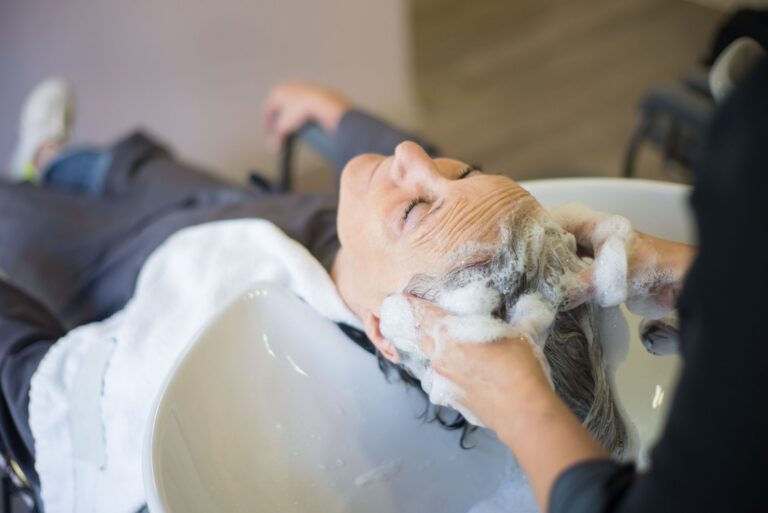 Femme détendue pendant le lavage et le massage du cuir chevelu avec une mousse de shampoing