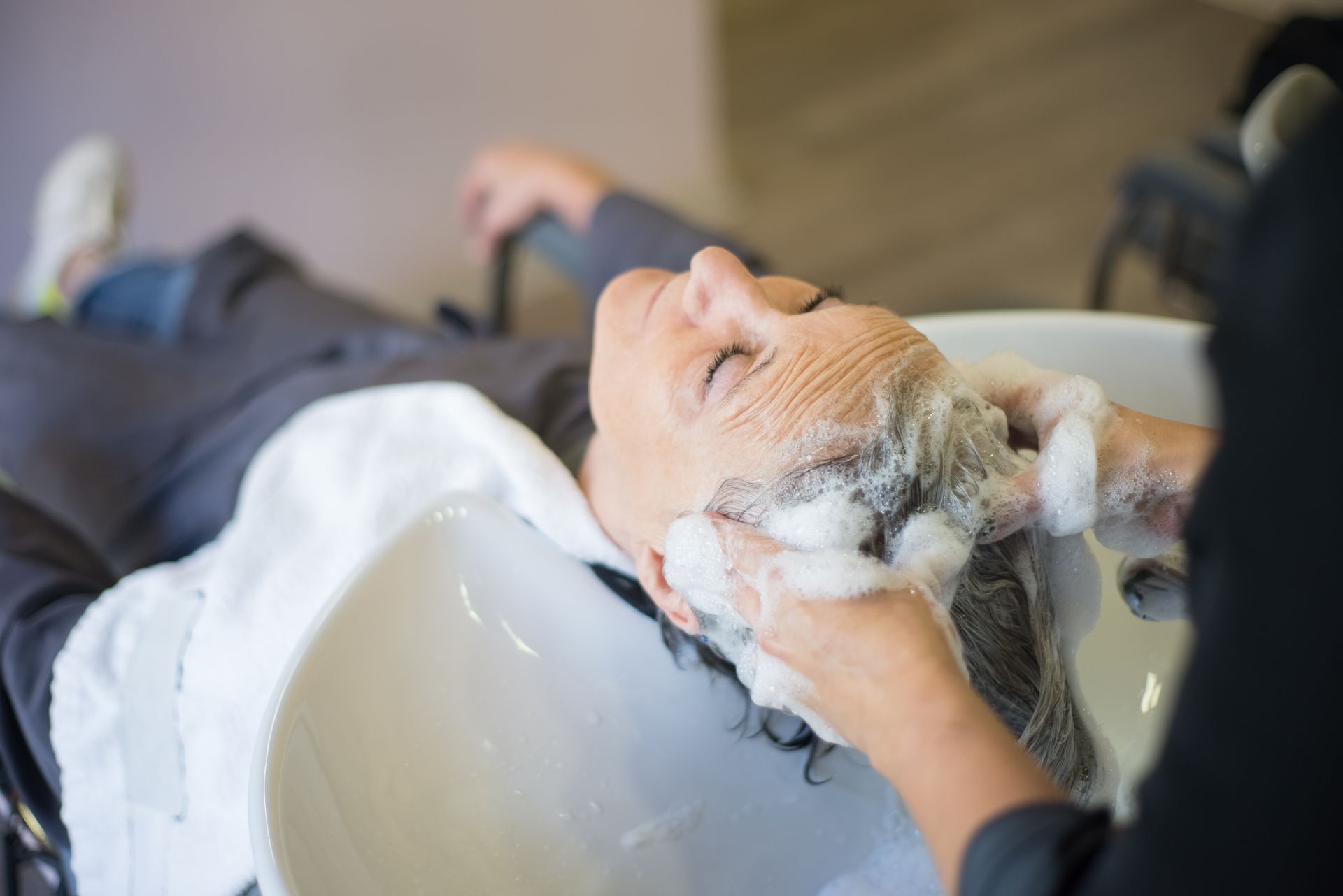 Femme détendue pendant le lavage et le massage du cuir chevelu avec une mousse de shampoing
