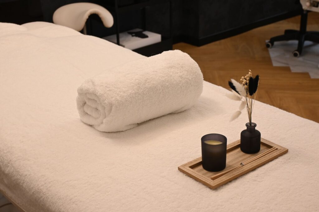 Table de massage avec serviette roulée et bougie, prête pour une séance